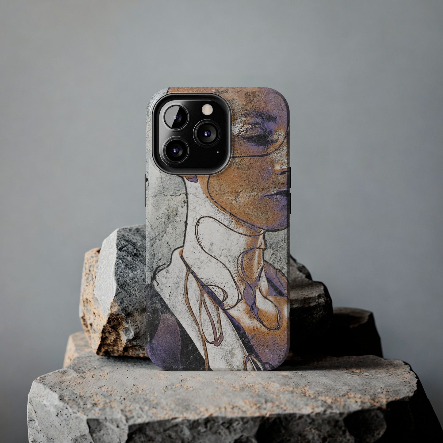 Alternative art phone case standing on textured stones in soft lighting