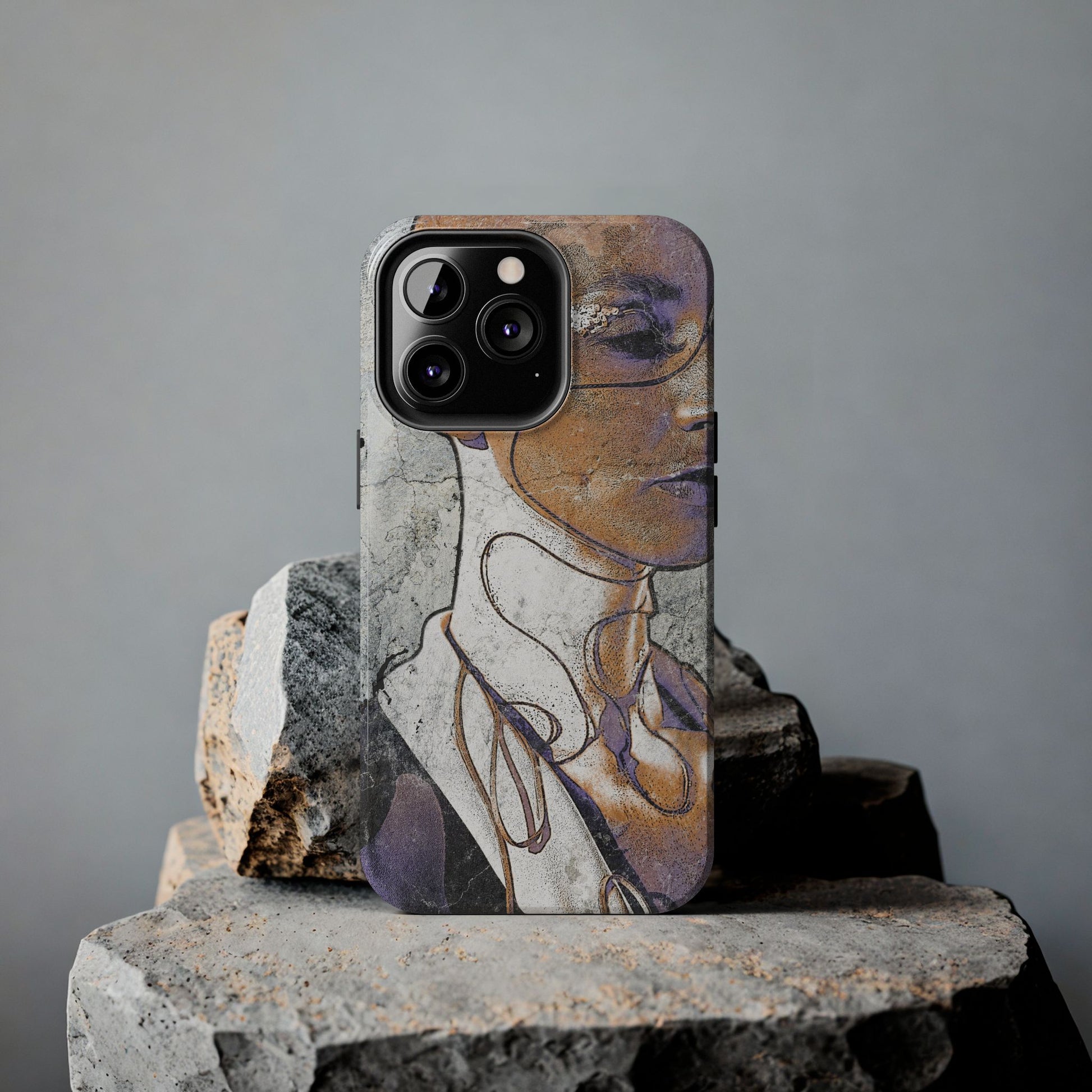 Alternative art phone case standing on textured stones in soft lighting